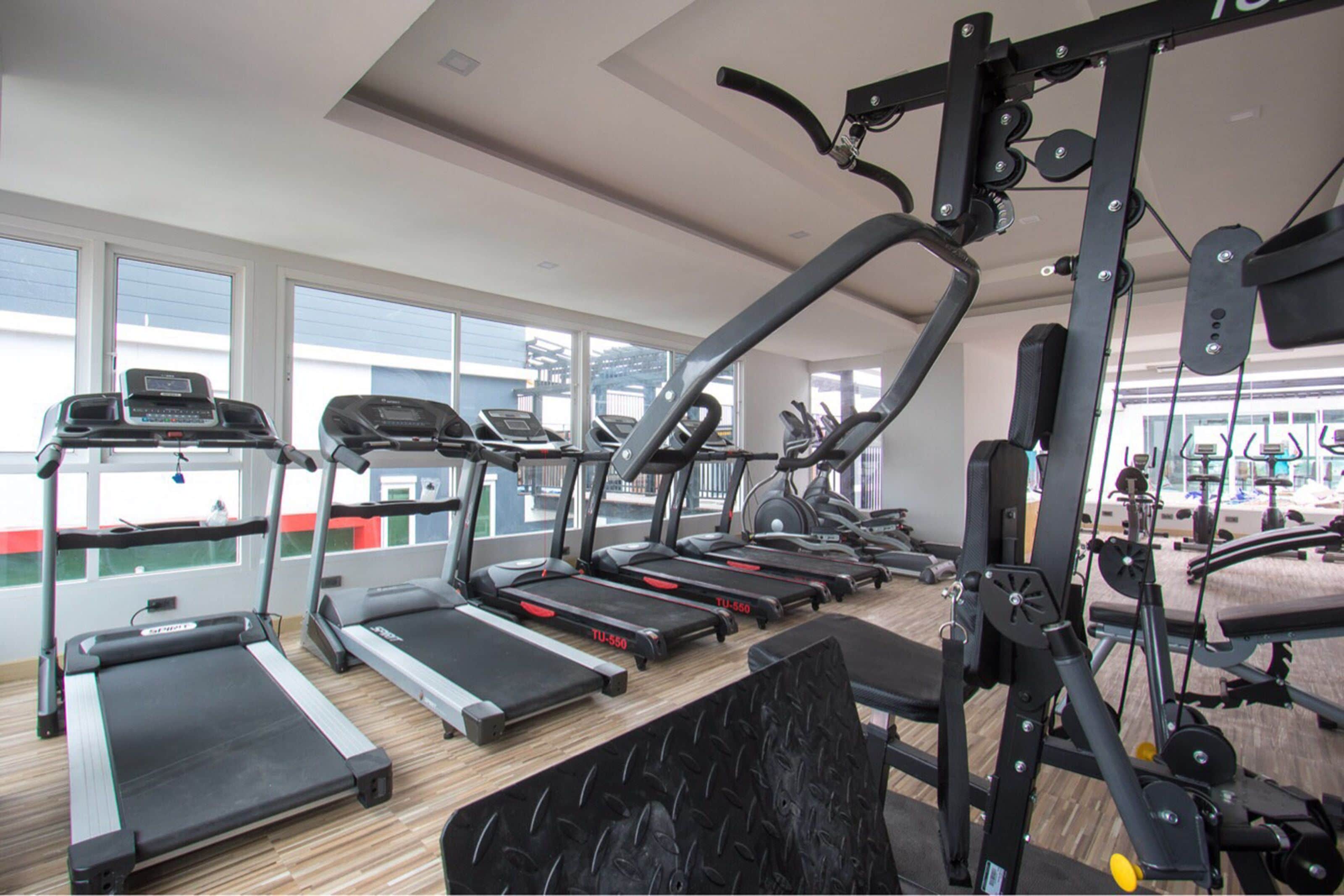 A gym with treadmills, elliptical machines, and weightlifting equipment.