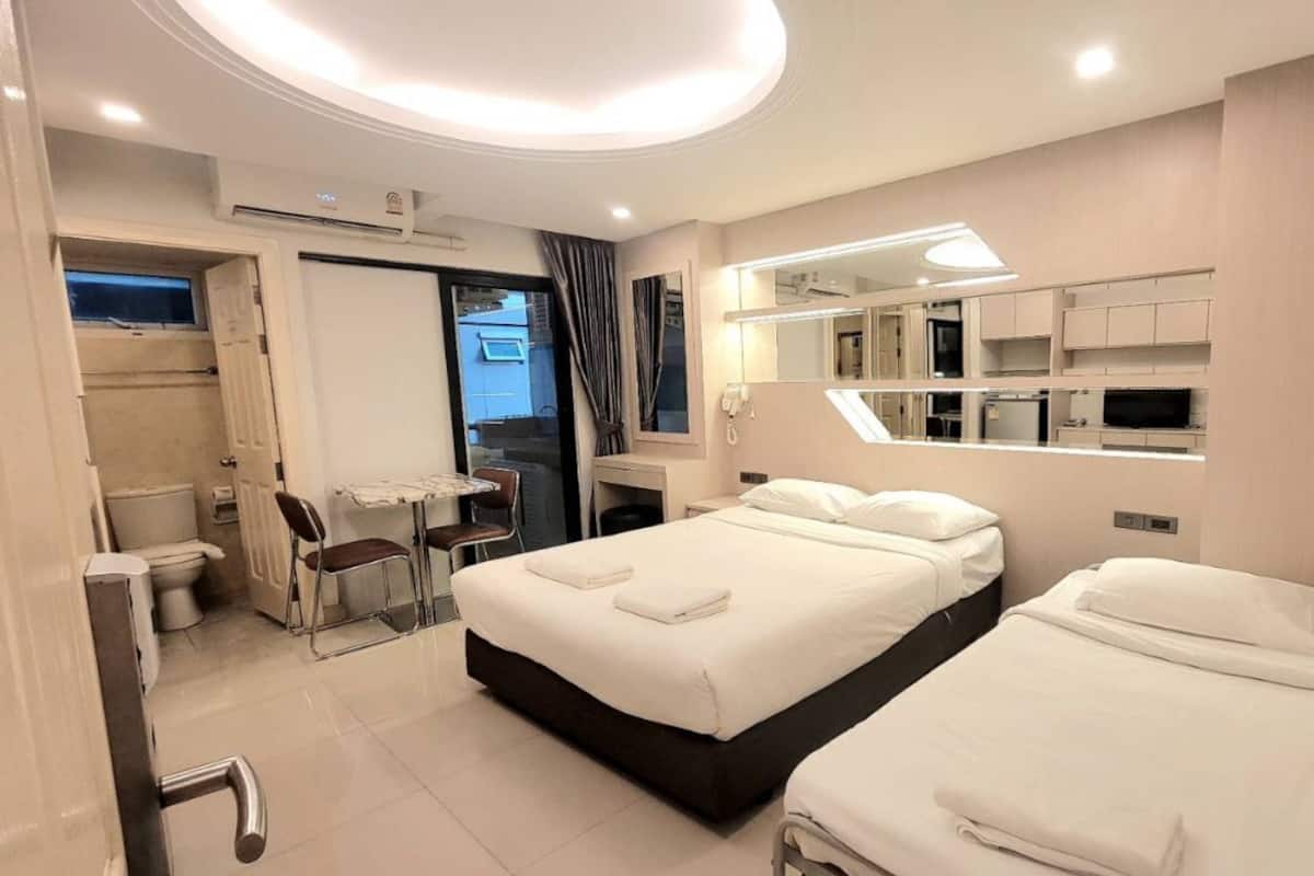 A hotel room with two beds, a desk, a chair, a mirror, and a TV.
