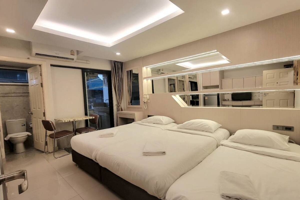 A modern hotel room with a large bed, a desk, a chair, a mirror, and a bathroom.