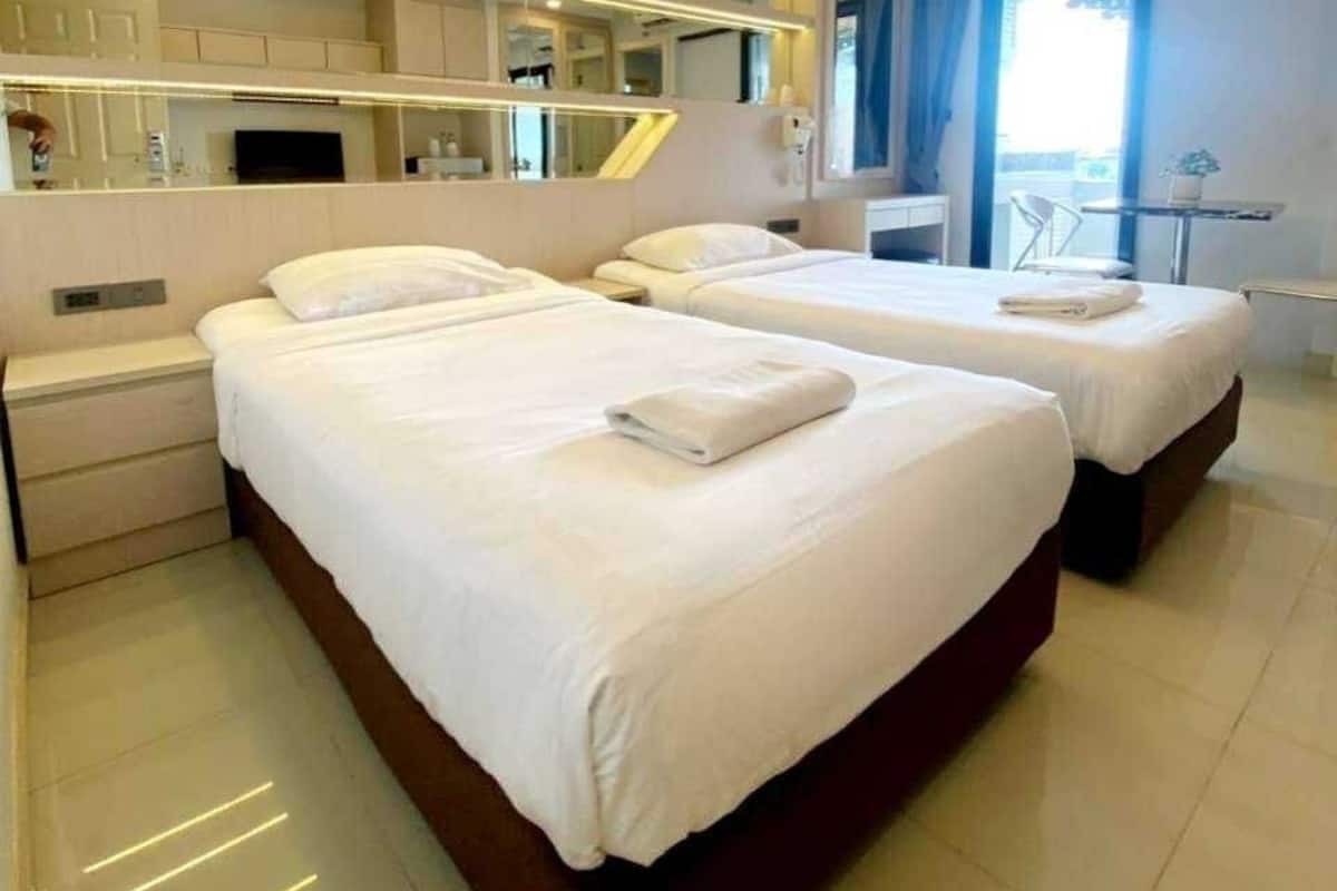 A modern hotel room with two beds, a large mirror, and a small balcony.