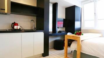 Una cocina moderna con armarios blancos, encimera negra y una mesa de madera con un jarrón de flores.
