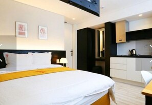A hotel room with a bed, a desk, and a kitchenette. - 216 Dong Jeju Swiss Village (Jeju City)