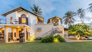Uma casa de dois andares com varanda, escadaria e área de piscina.