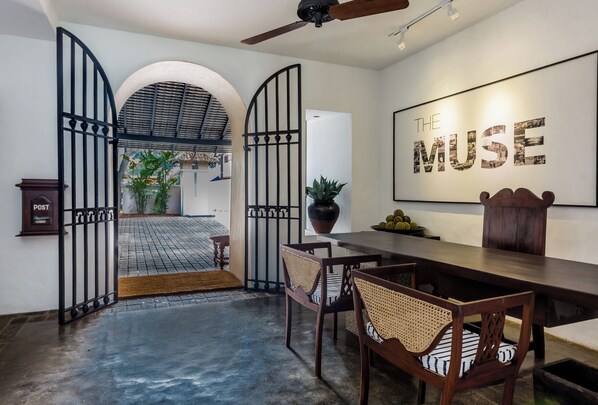 A dining area with a high ceiling, a ceiling fan, and a wall-mounted sign reading "THE MUSE".
