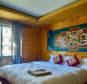 Una habitación de madera con una cama, un ventanal con cortinas y un cuadro decorativo en la pared.