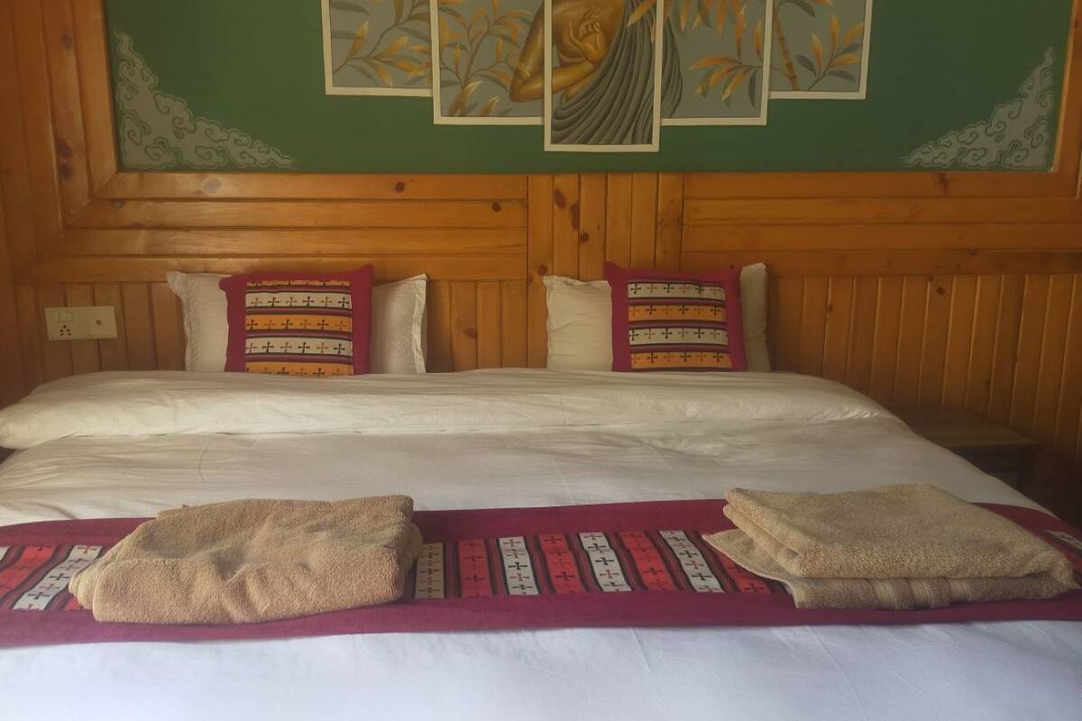 A bed with white linens, two pillows, and a blanket. There are three framed pictures above the bed.