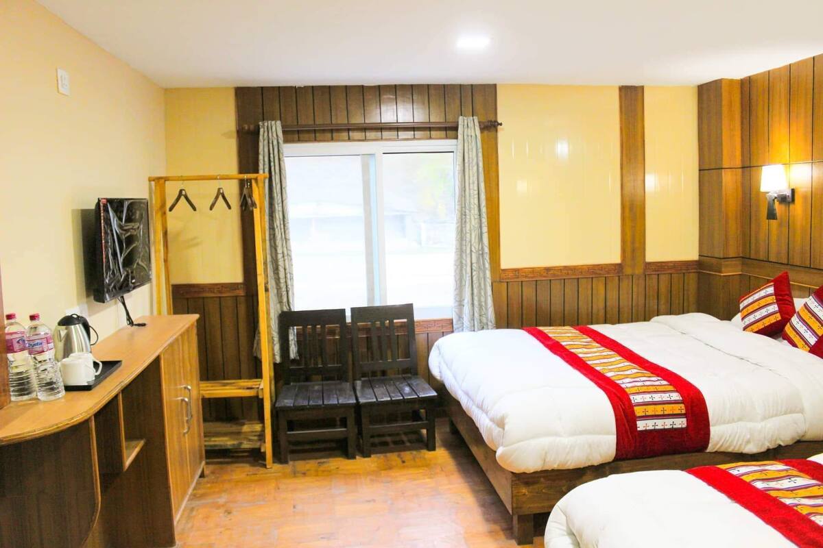 A hotel room with a bed, a desk, a chair, a television, and a window with curtains.