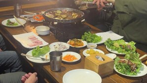 A dining table with various dishes, including a hot pot, salad, and sliced meats. - Hotel Grand Shambala (Muktinath)