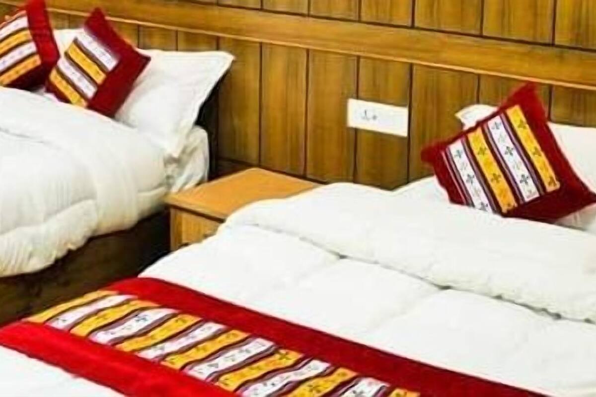 Two single beds with white bedding and red and yellow striped blankets, wooden headboards, and a small wooden nightstand between them.