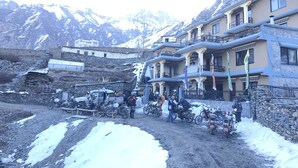 A hotel with a multi-story structure, a stone wall, and a mountainous backdrop. - Hotel Grand Shambala (Muktinath)
