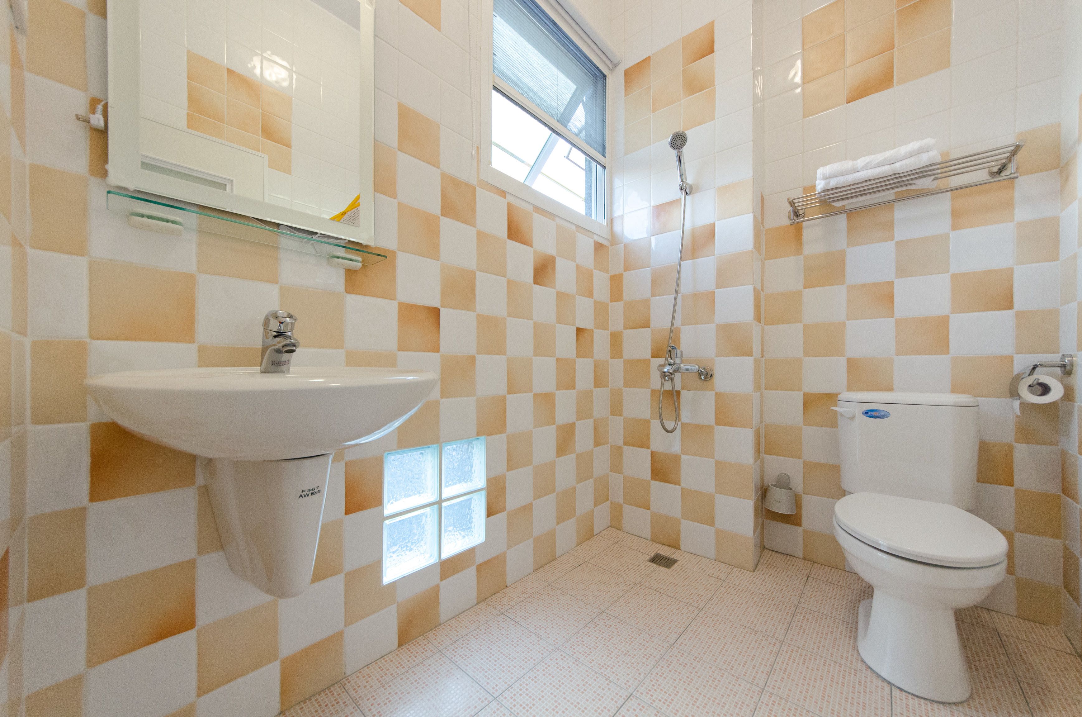 Un baño con piso de baldosas a cuadros, un lavamanos, un inodoro, una ducha y una ventana.