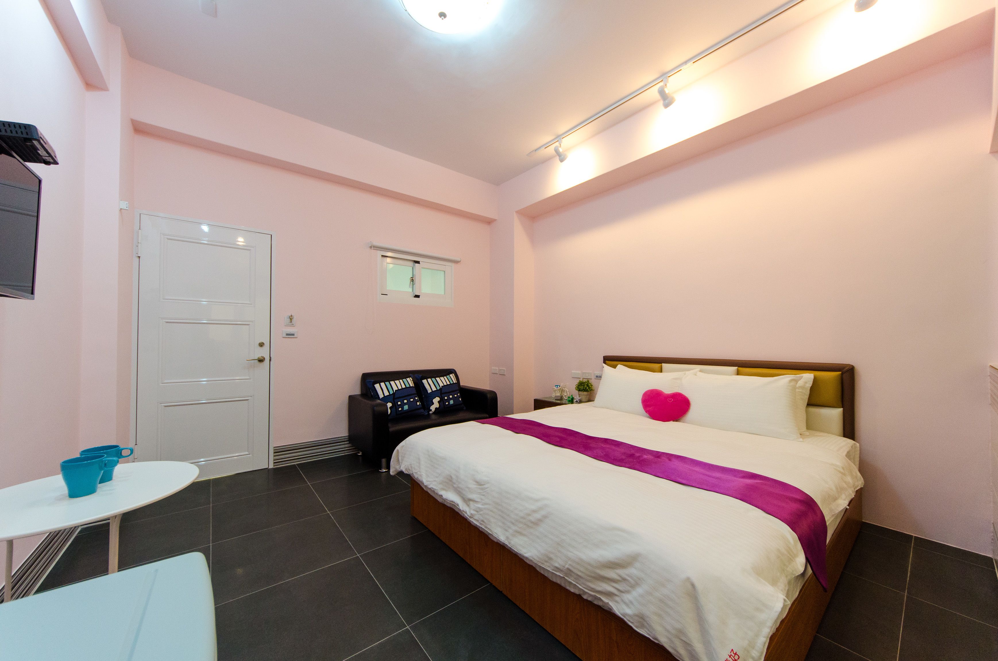 Quarto com cama, uma mesinha, cadeira, escrivaninha e porta.