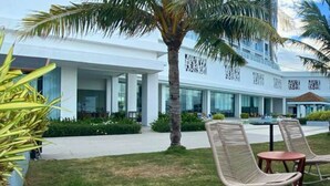 A modern hotel with a white facade, a palm tree, and outdoor seating area. - Arterra Hotel and Resort (Lapu-Lapu)