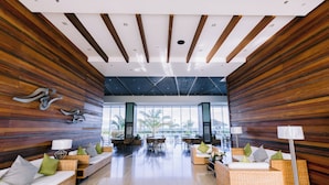 A spacious lobby with wooden paneling, wicker furniture, and a view of palm trees. - Arterra Hotel and Resort (Lapu-Lapu)