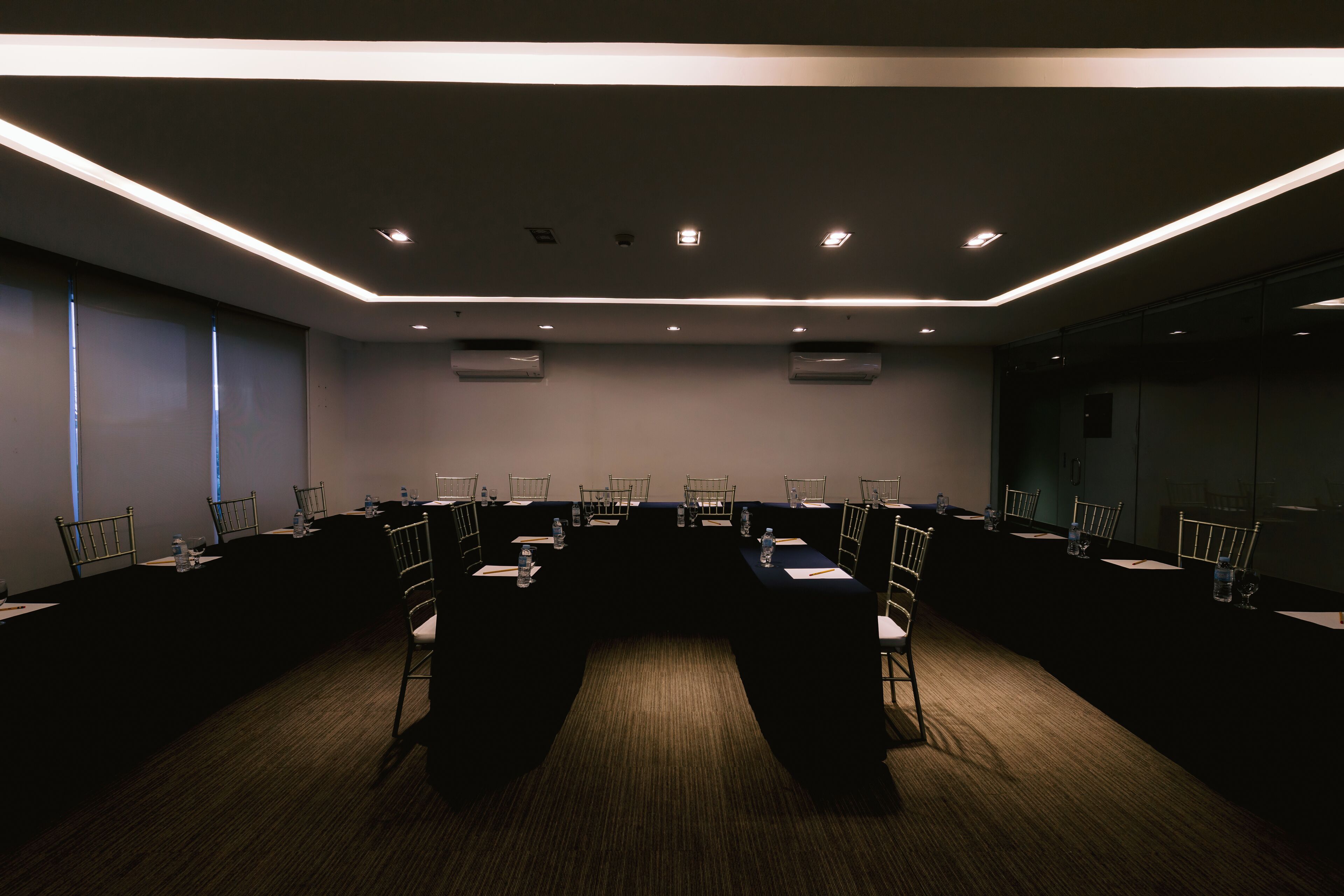 A conference room with a long table, chairs, and ceiling lights.