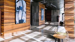 A modern lobby with wooden panel walls, abstract art, a wicker chair, and a polished floor. - Arterra Hotel and Resort (Lapu-Lapu)