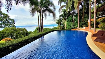 Una piscina al aire libre, sombrillas, sillones reclinables de piscina