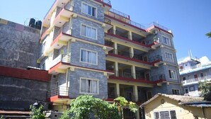 Un edificio de varios pisos con balcones, techo plano y un tanque de agua visible.