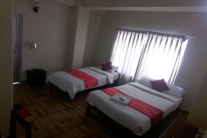 A room with two single beds, each with a red and white bedspread, a small bedside table, and a window with curtains. - Hotel God Pigeon (Pokhara)