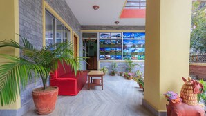 Un pasillo con un sofá rojo, una mesa de madera y plantas en macetas.