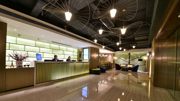 A modern hotel lobby with a reception desk, seating area, and a large digital screen. - ibis Styles XM Zhongshan (Xiamen)