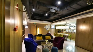 A modern lobby with a sofa, chairs, and a small table with a vase. - ibis Styles XM Zhongshan (Xiamen)