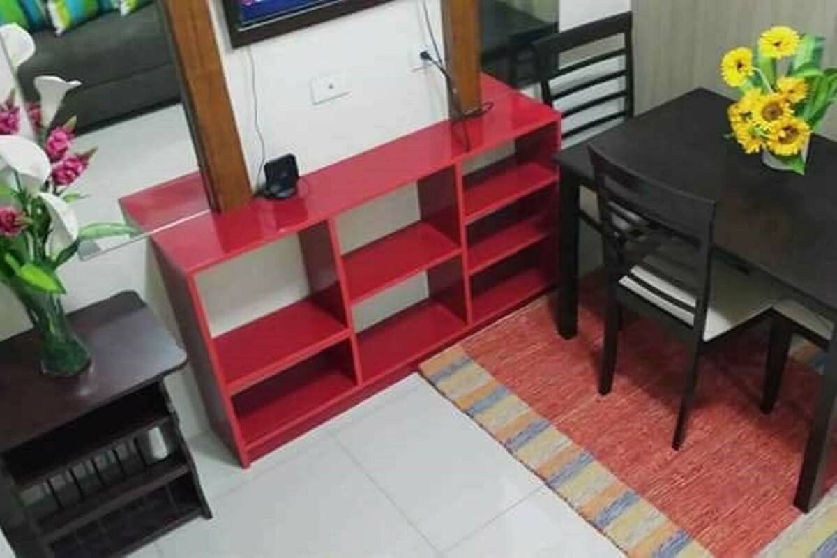 A dining area with a black table, red shelving unit, and a vase of sunflowers.