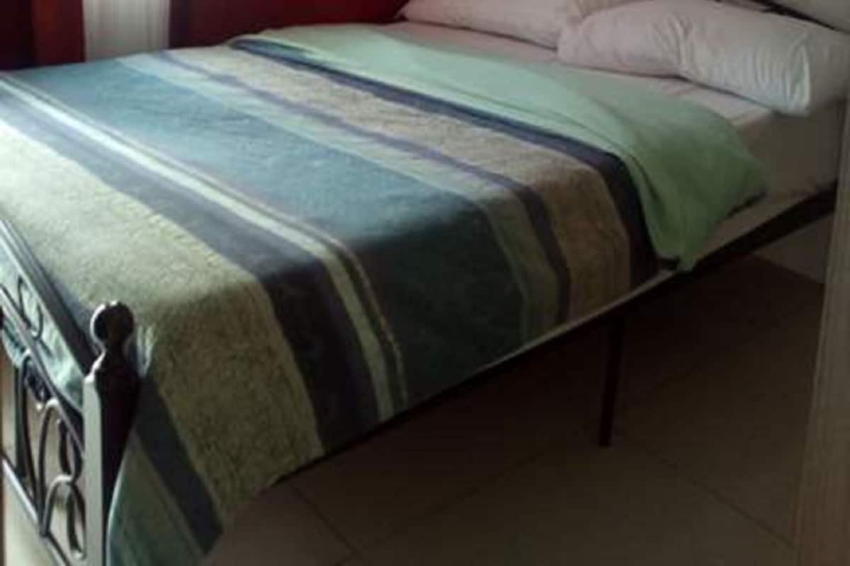 A bed with a striped bedspread, a pillow, and a headboard.