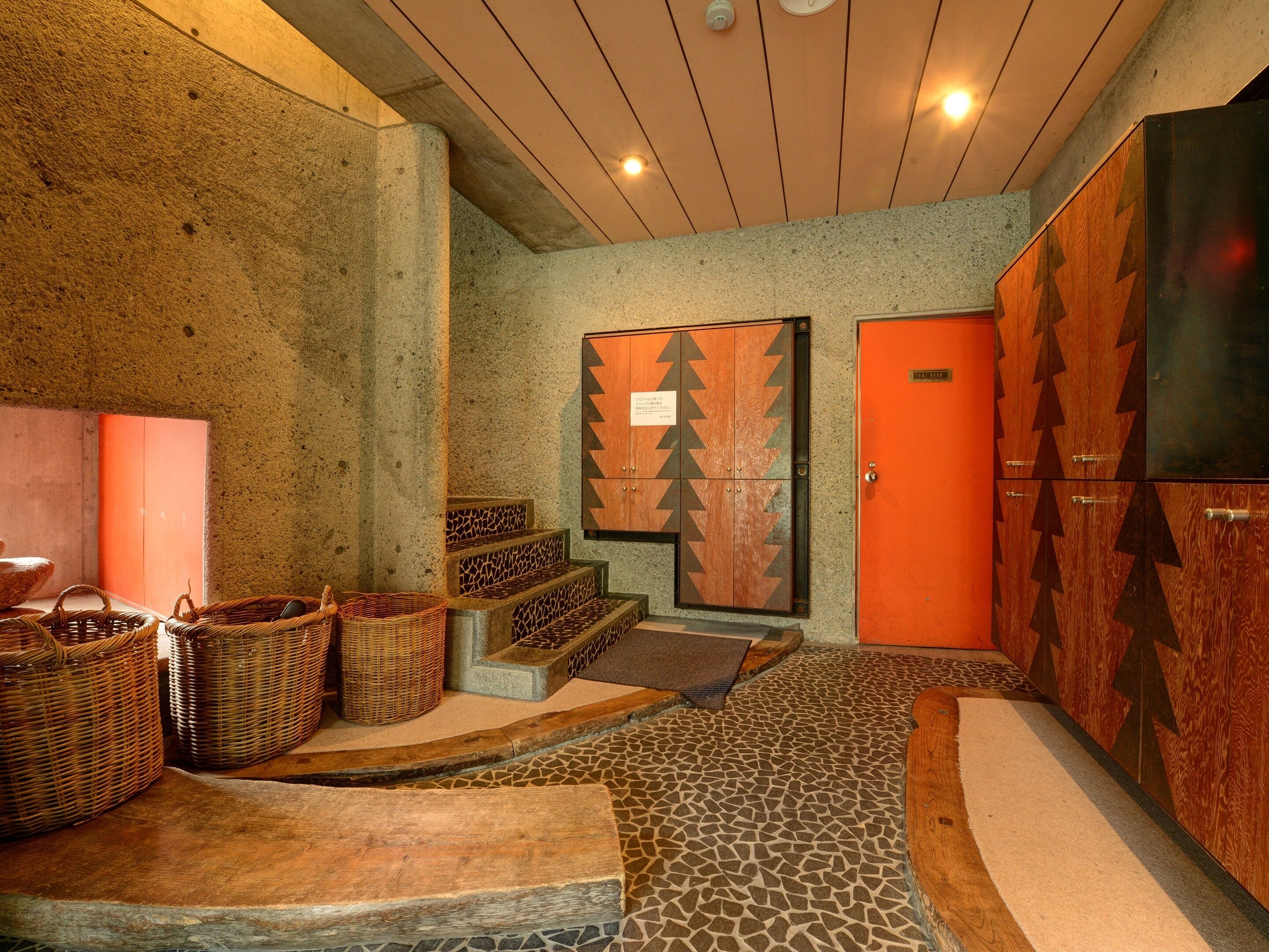Un vestíbulo con pared de piedra, una escalera de madera y una zona de recepción con un mueble de madera y una puerta.