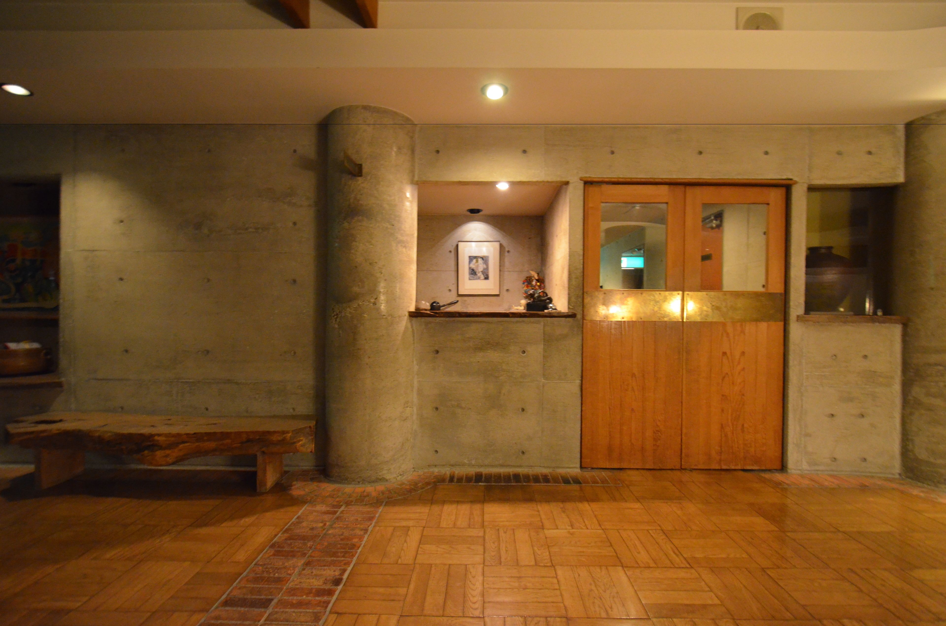 A room with a wooden bench, a wooden door, and a tiled floor.