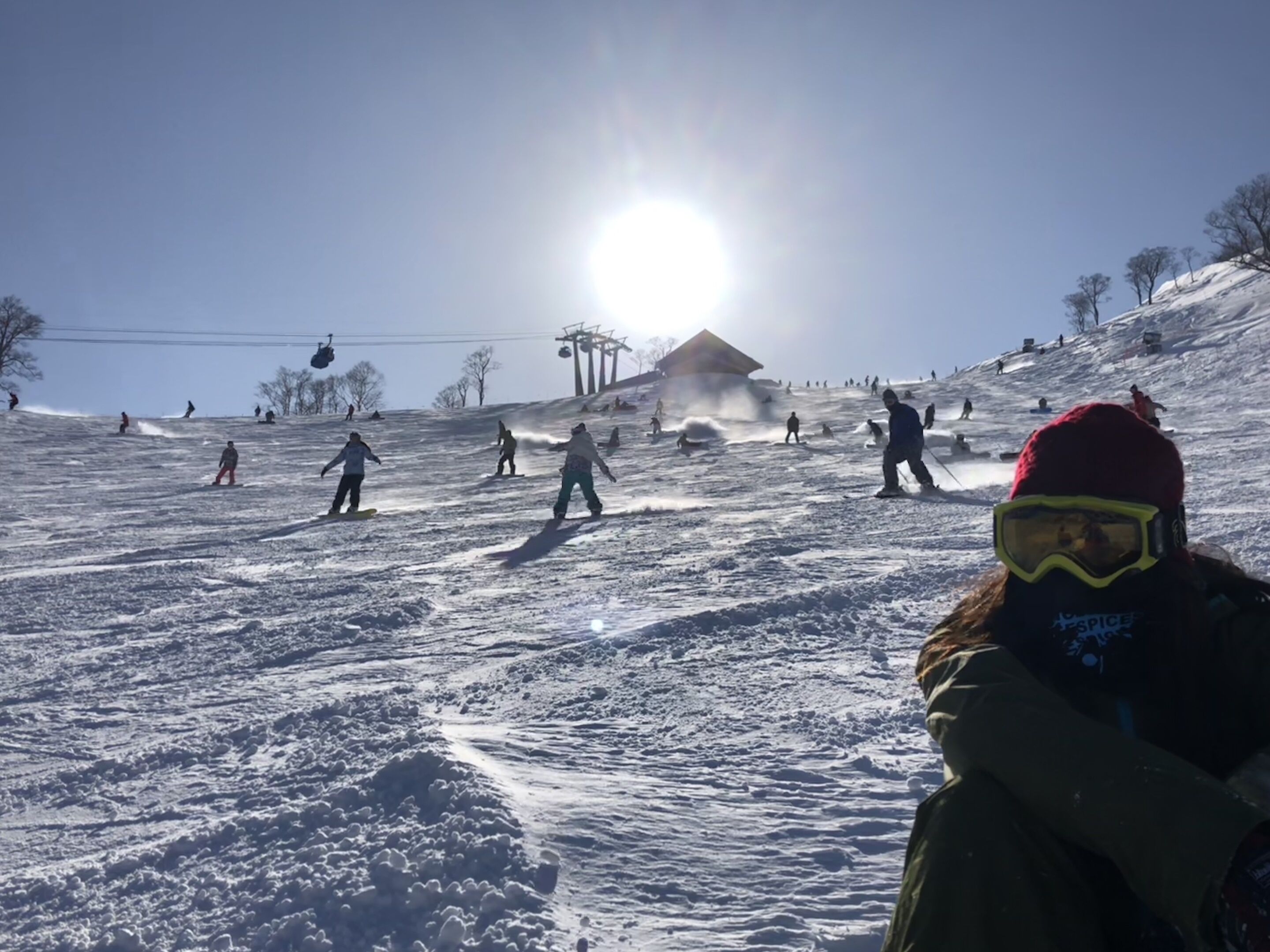 A snowy ski slope with skiers and a ski lift in the background.