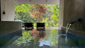 Piscina interior con agua cristalina, dos bancos y vista a árboles fuera.