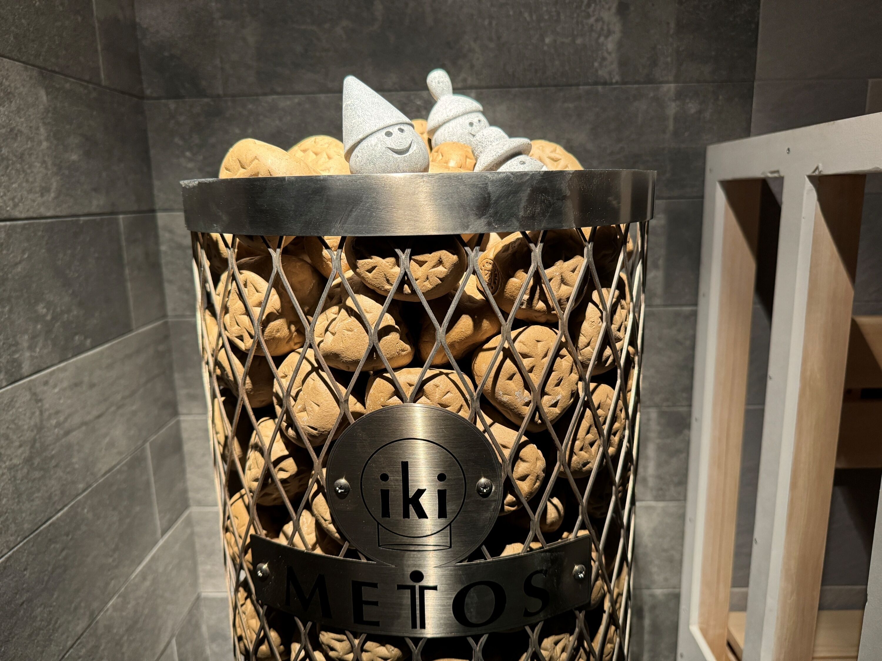 Un panier en métal rempli de biscuits et une plaque en métal portant l’inscription « IKI METOS ».