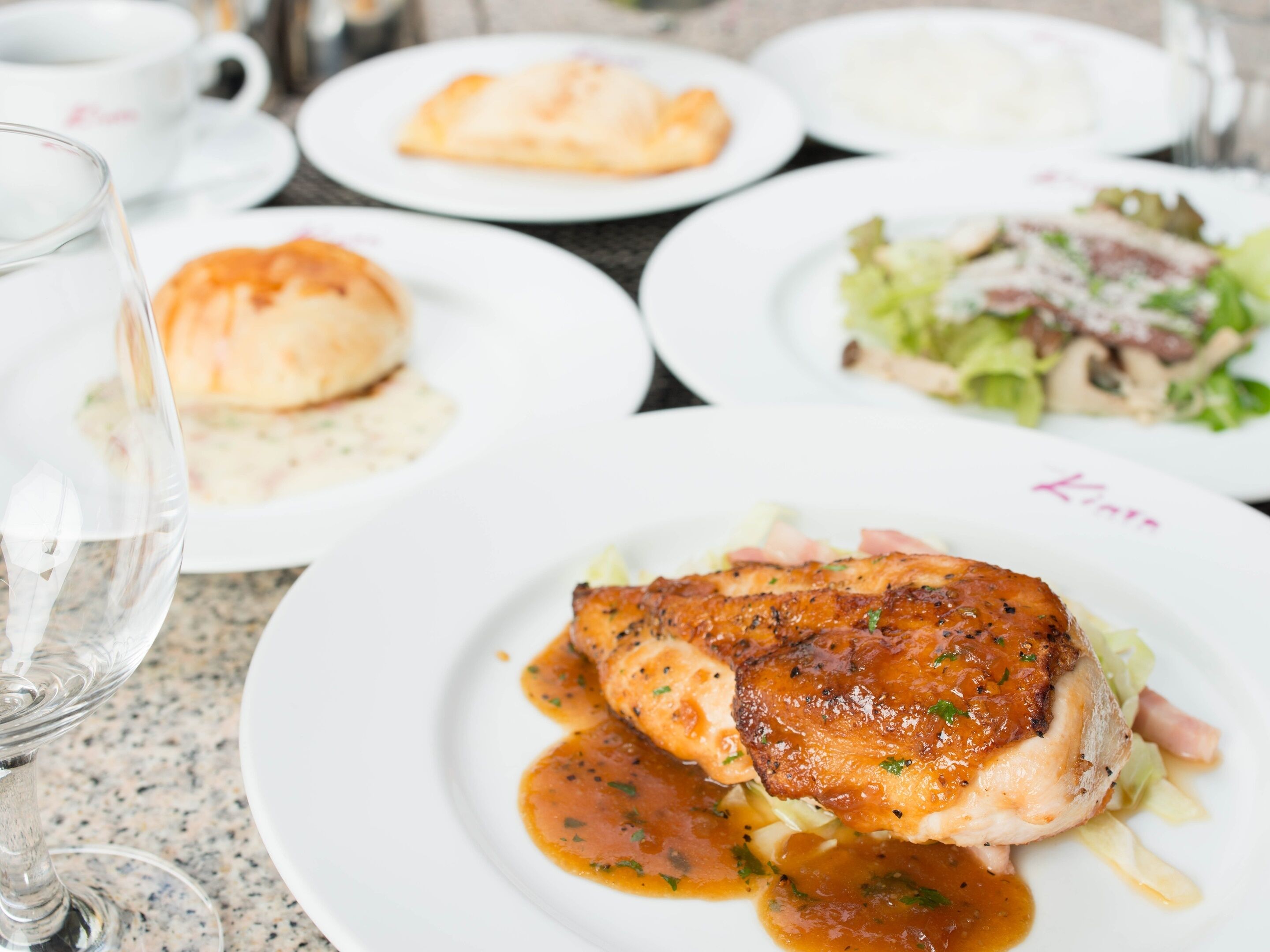 A dining table with various dishes including a plate of chicken with sauce, a salad, and other food items.