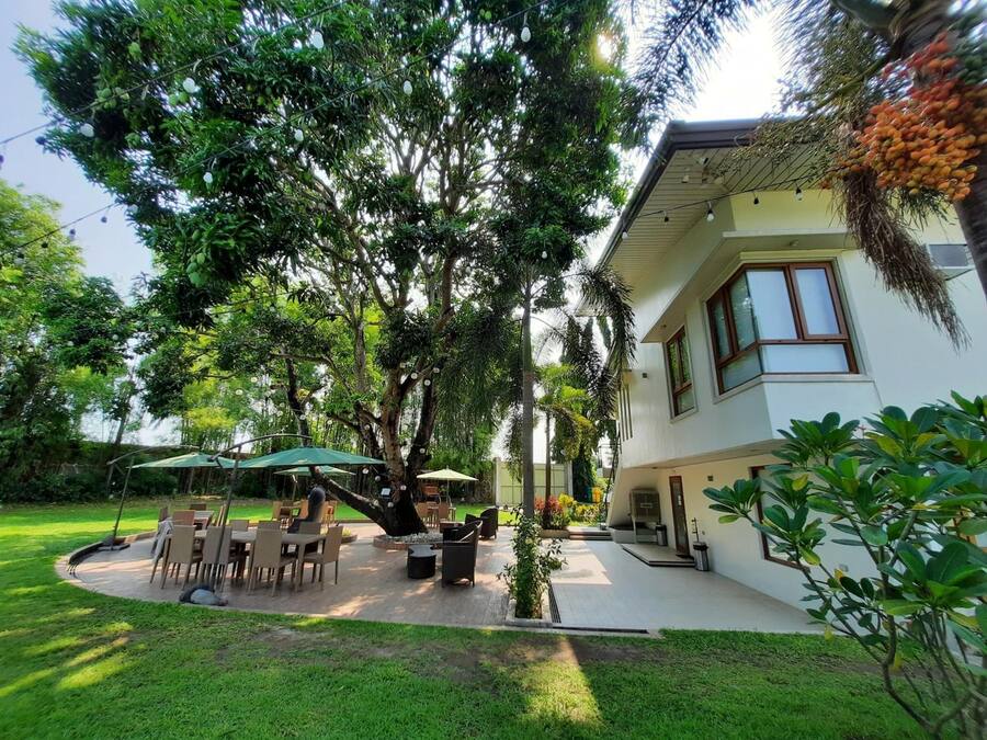 A house with a patio area featuring outdoor furniture and a large tree.