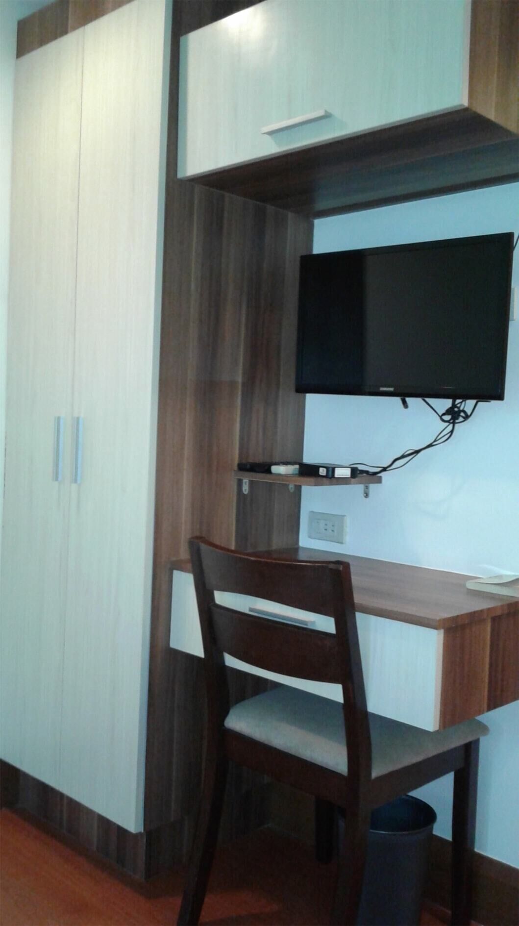 A small office space with a desk, chair, TV, and storage cabinets.