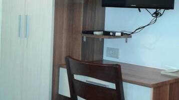 A small office space with a desk, chair, TV, and storage cabinets.