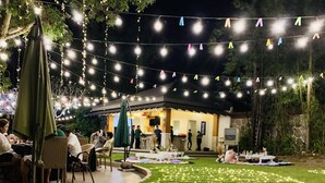 An outdoor dining area with string lights and tables. - Estancia De Lorenzo Tarlac (Capas)