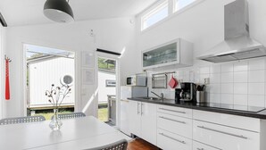 Une cuisine moderne avec des meubles blancs, un plan de travail noir et un coin repas comprenant une table et des chaises blanches.