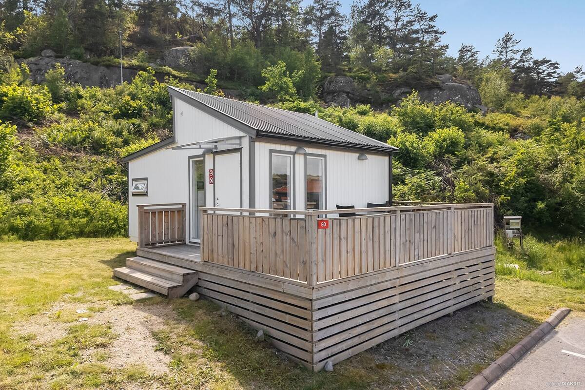 A small, single-story cabin with a sloped roof, a wooden deck, and a small porch.