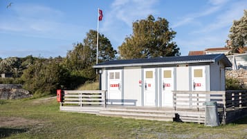 A small, single-story building with a flat roof, a flagpole with a flag, and a wooden fence.