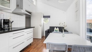 Une cuisine moderne avec des meubles blancs, un plan de travail noir et un coin repas comprenant une table blanche et des chaises grises.