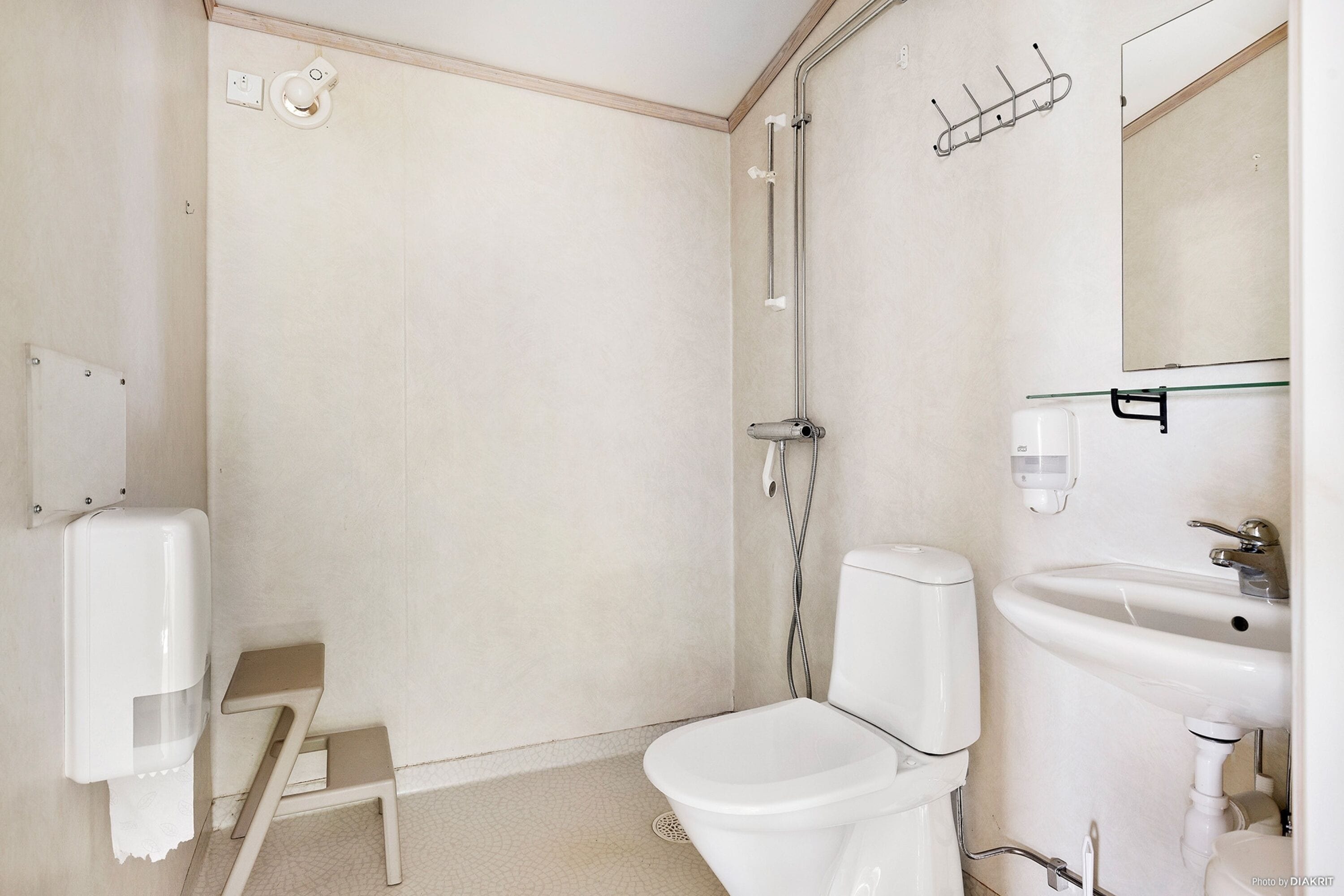 A small, clean bathroom with a toilet, sink, and shower.
