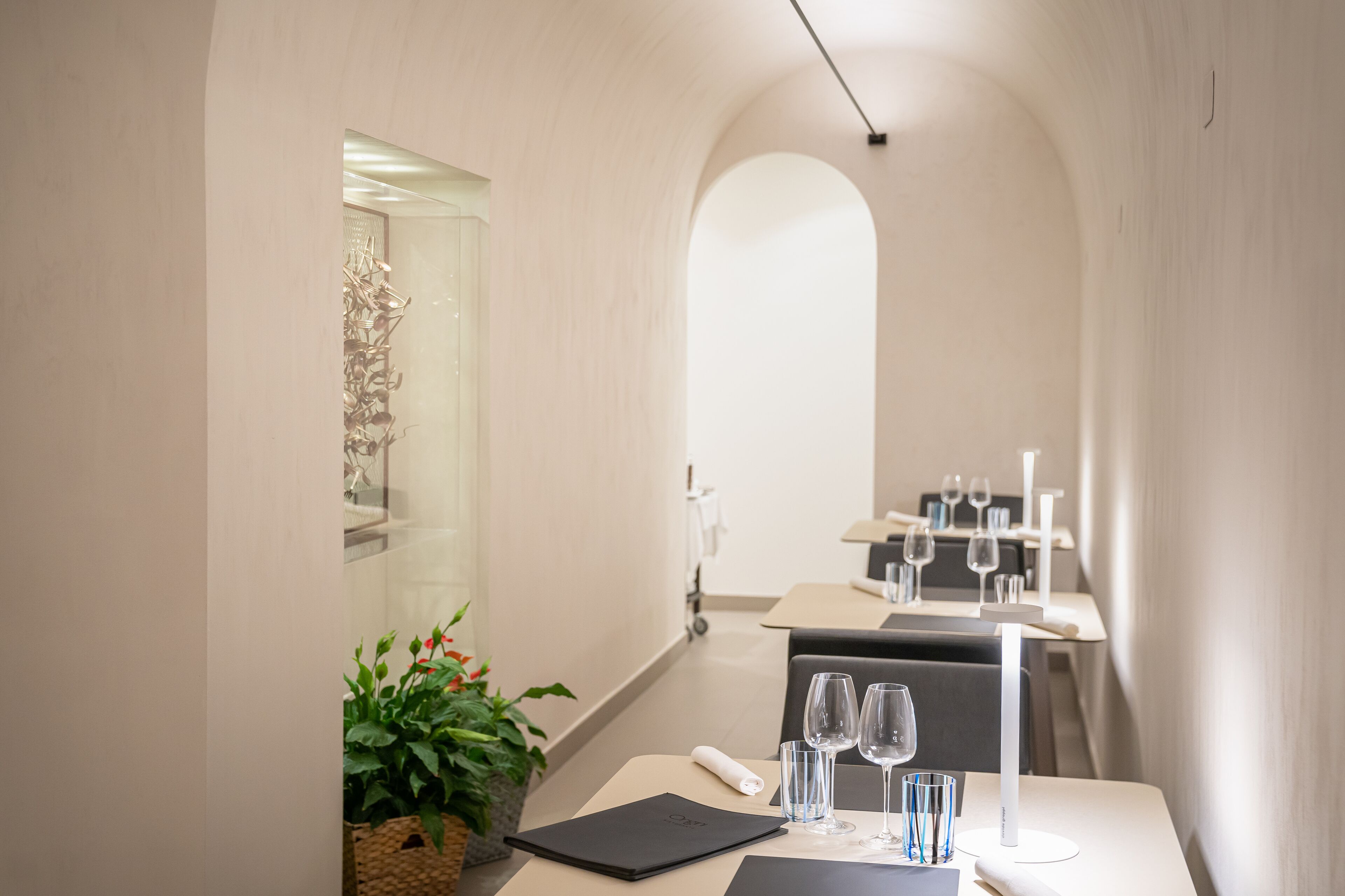 A modern dining area with a long table, chairs, and a glass partition.