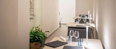A modern dining area with a long table, chairs, and a glass partition.