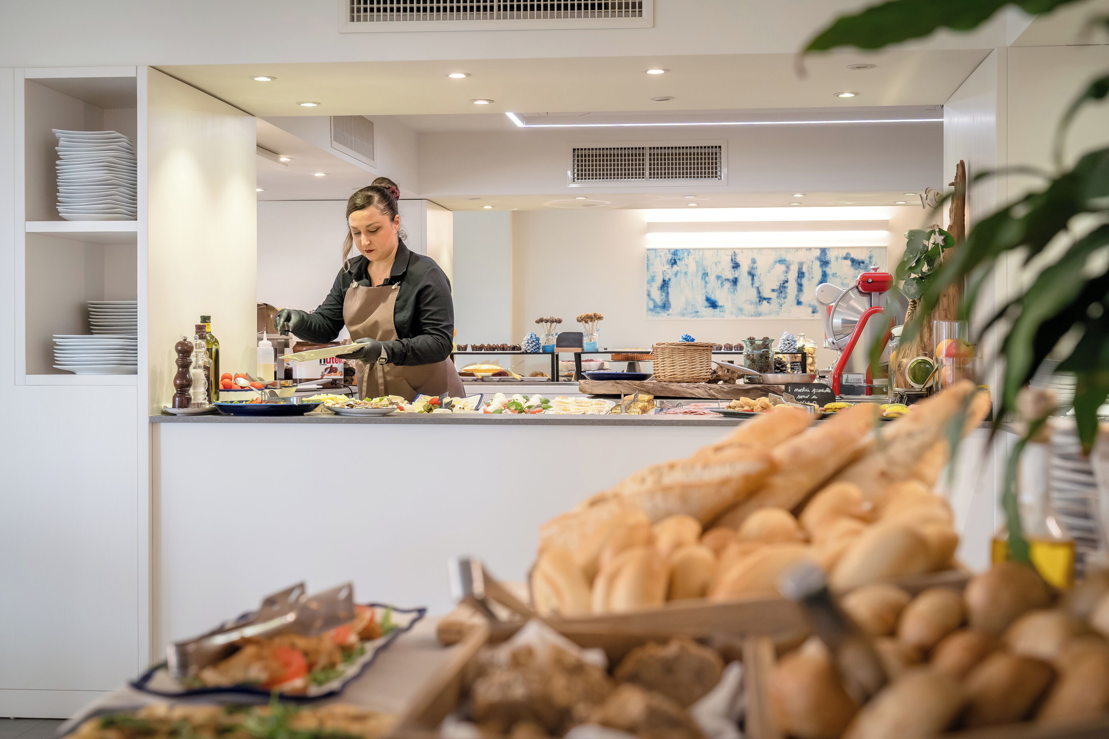 A buffet setup with various food items and a person serving.