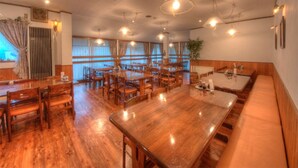 A spacious dining area with wooden tables and chairs, pendant lighting, and large windows. - Allumeur (Minamiuonuma)