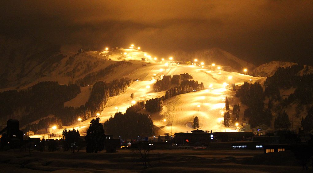 A snow-covered mountain with a ski lift and buildings at the base.