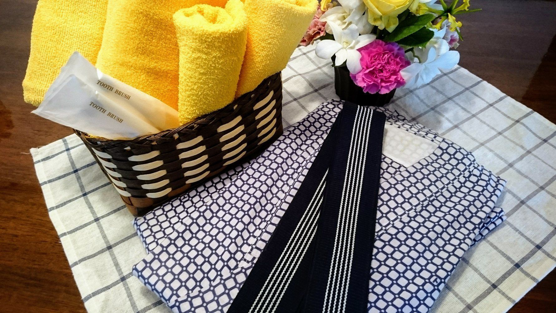 A checkered tablecloth, a striped tie, yellow towels, and a basket with a toothbrush.