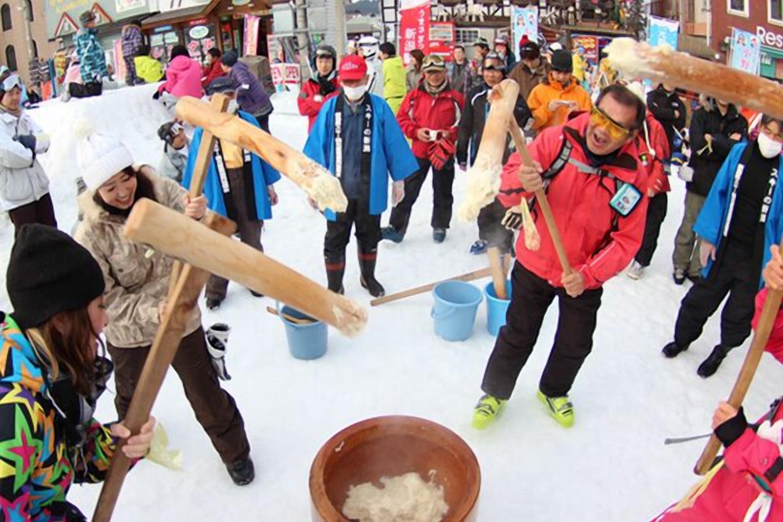 A group of people participating in a snow event, using wooden tools to interact with snow.